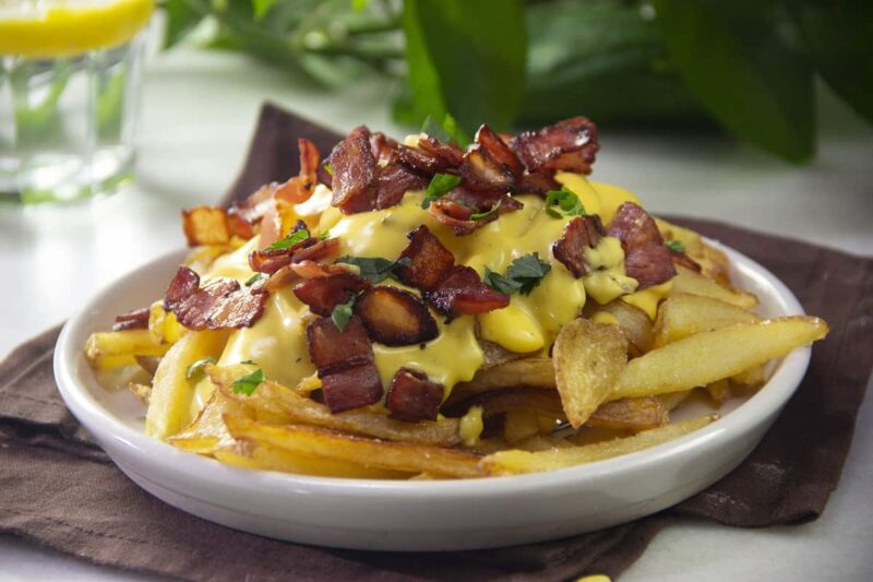 plato de Papas fritas con queso cheddar y tocino